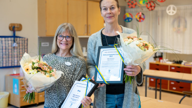 Två kvinnor med diplom och blommor