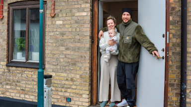 två vuxna och ett spädbarn i dörren till sitt hus i Trelleborg.
