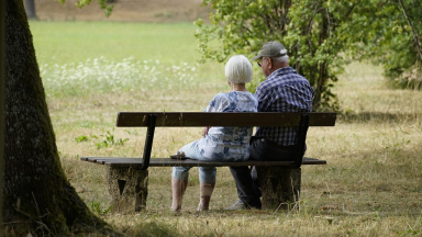 Ett äldre par sitter tillsammans på en parkbänk